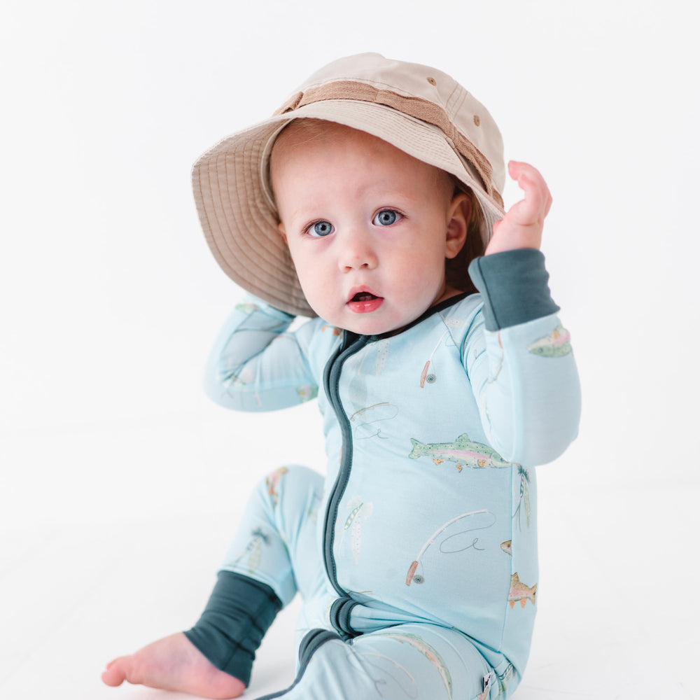 
                      
                        Baby wearing a light blue onesie with animal prints and a beige hat on a white background
                      
                    