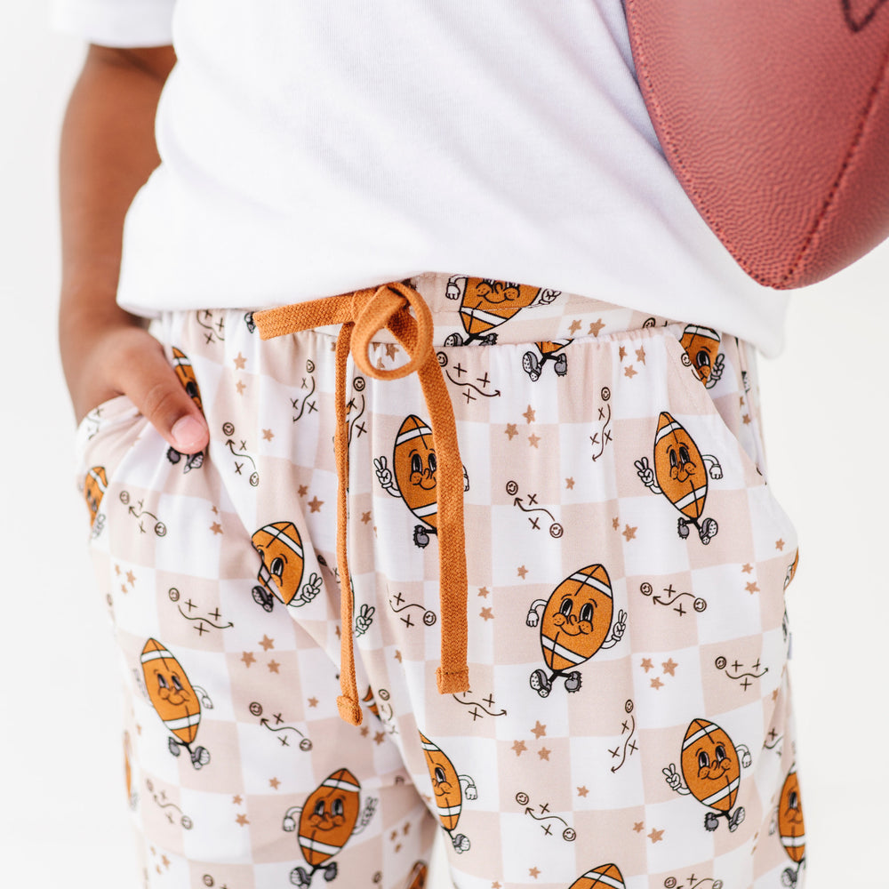 
                      
                        Person wearing pajama pants with football pattern holding a football.
                      
                    