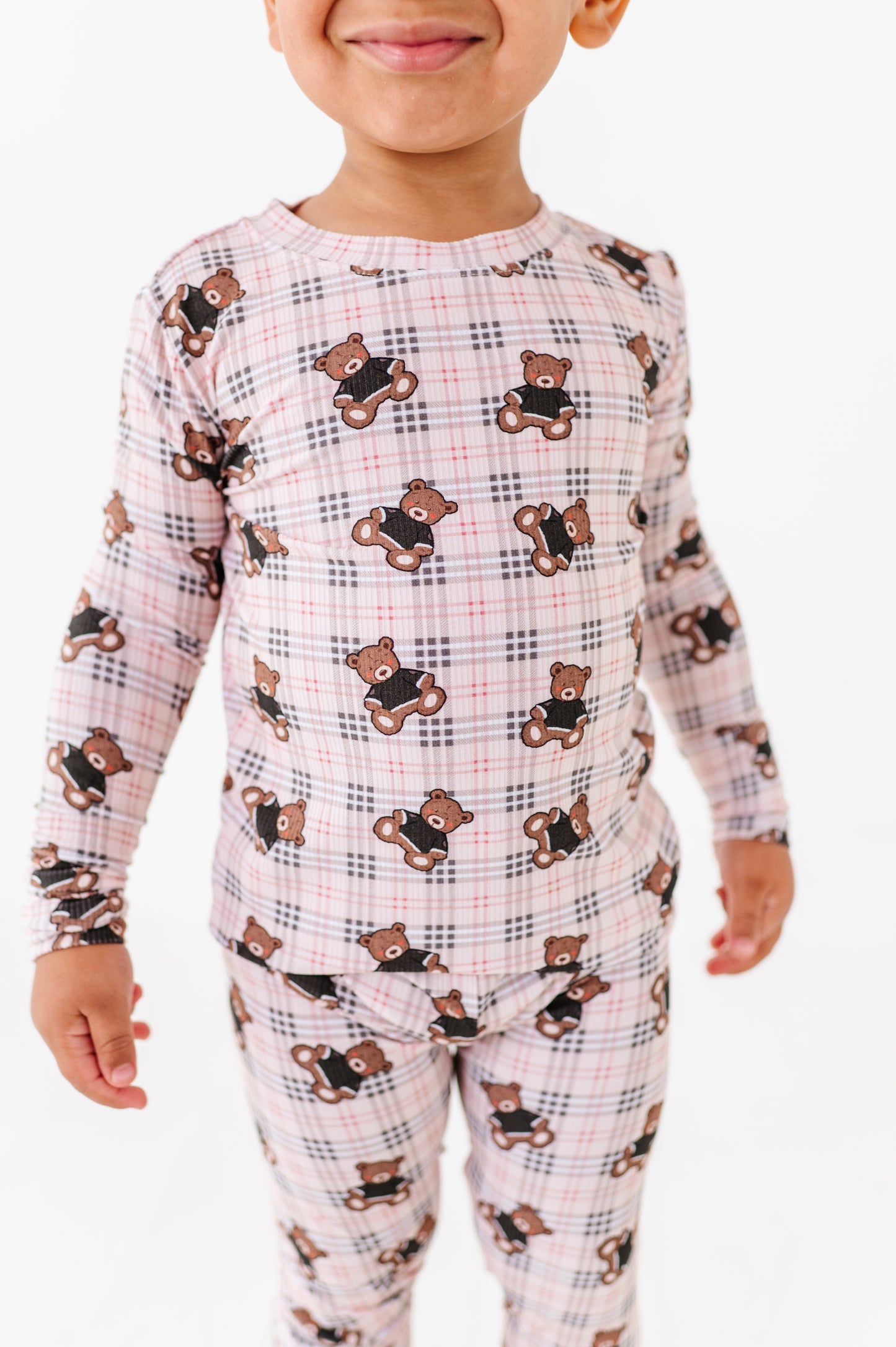 Child wearing pajamas with teddy bear pattern on a white background