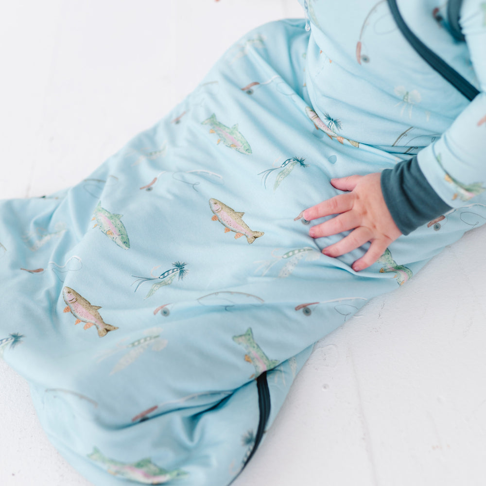 
                      
                        Baby wrapped in a blue swaddle with fish pattern on a white surface
                      
                    