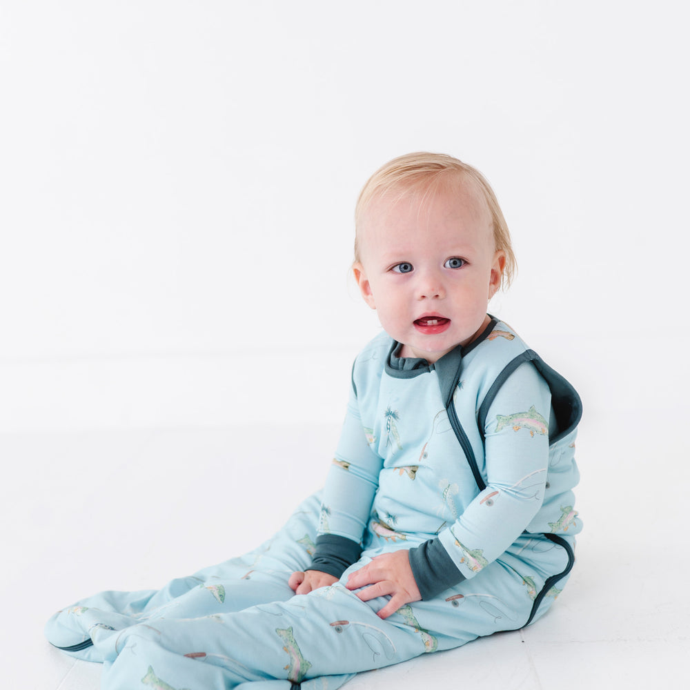 Baby in a blue sleeping bag with fish pattern on a white background