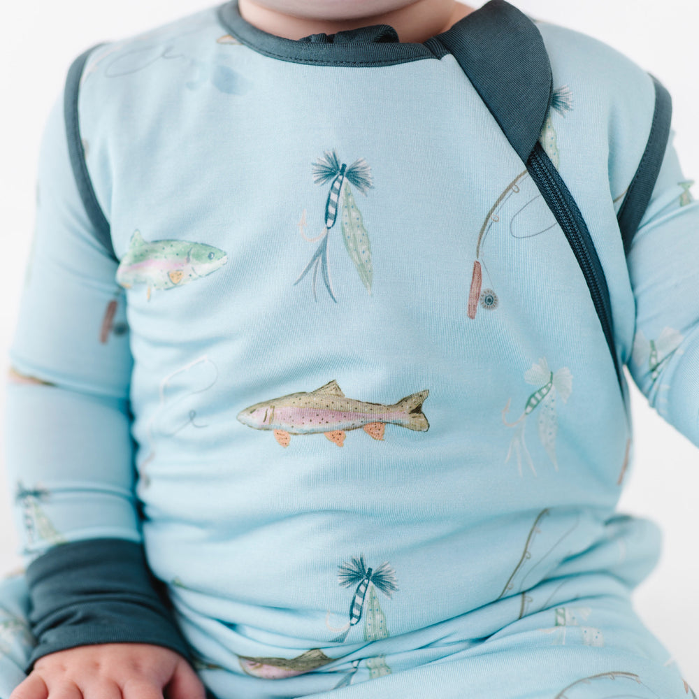 Baby wearing a blue outfit with fish pattern on a white background