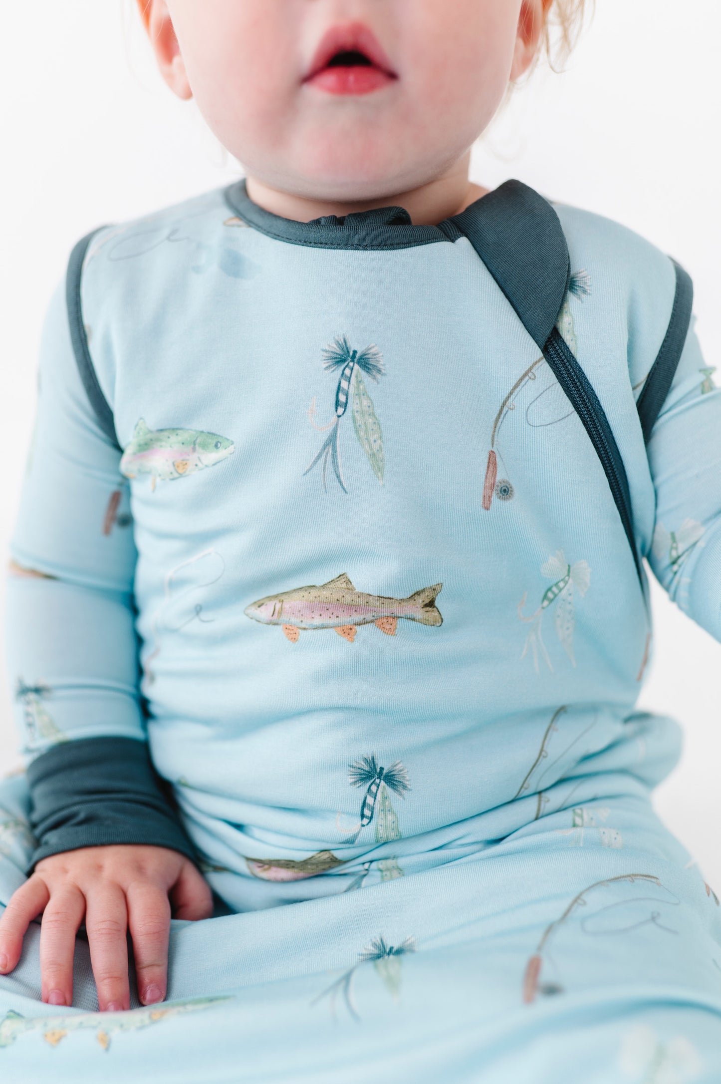Baby wearing a blue outfit with fish pattern on a white background