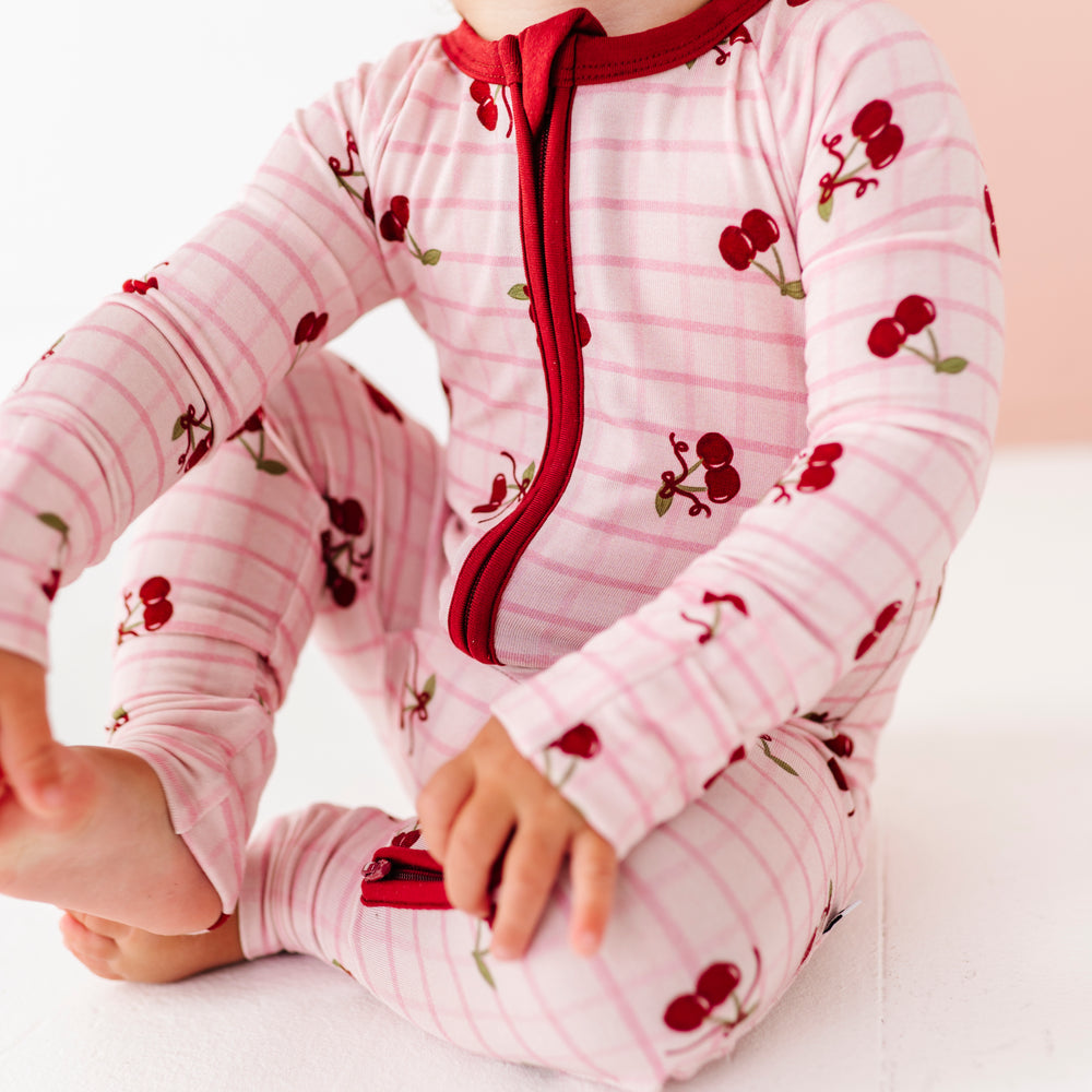 
                      
                        Baby wearing a pink outfit with red accents and cherry patterns on a white background
                      
                    