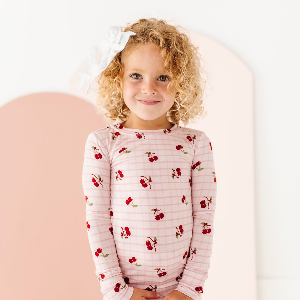 
                      
                        Child wearing a pajama set with cherry pattern on a white background
                      
                    