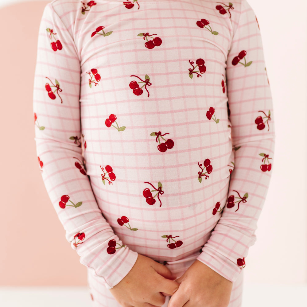Child wearing a pink pajama set with cherry pattern against a white background