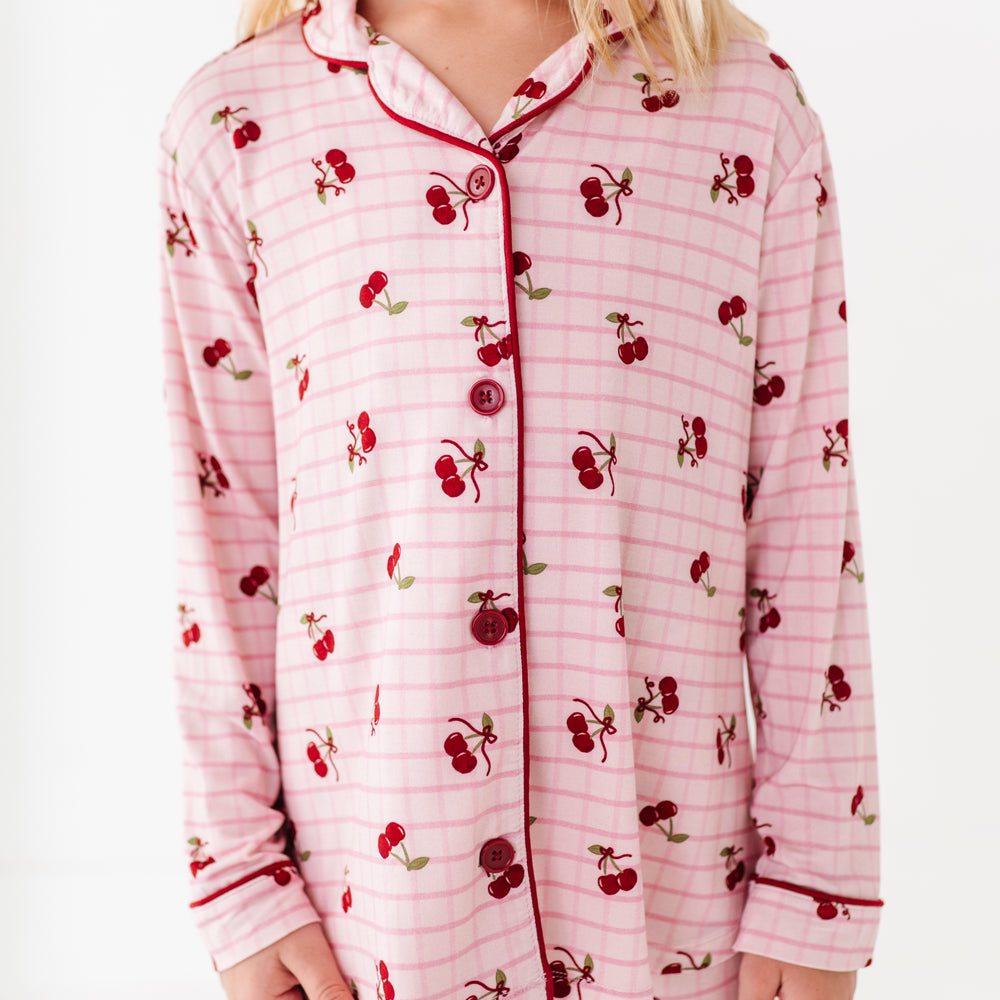 Child wearing a pink pajama set with cherry pattern on a white background