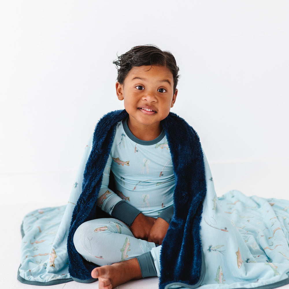 
                      
                        Child wrapped in a blue blanket with fish pattern on a white background
                      
                    