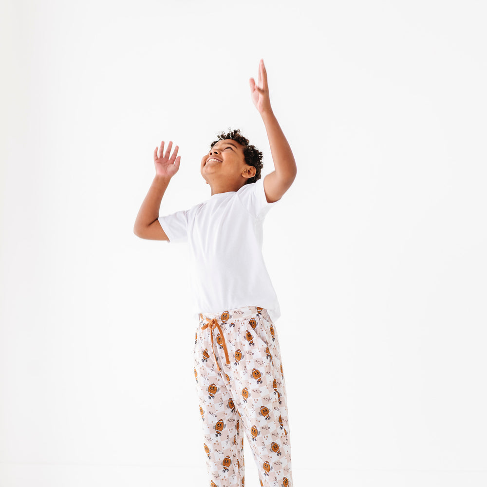 
                      
                        Child in pajama pants reaching up to catch a football on a white background
                      
                    