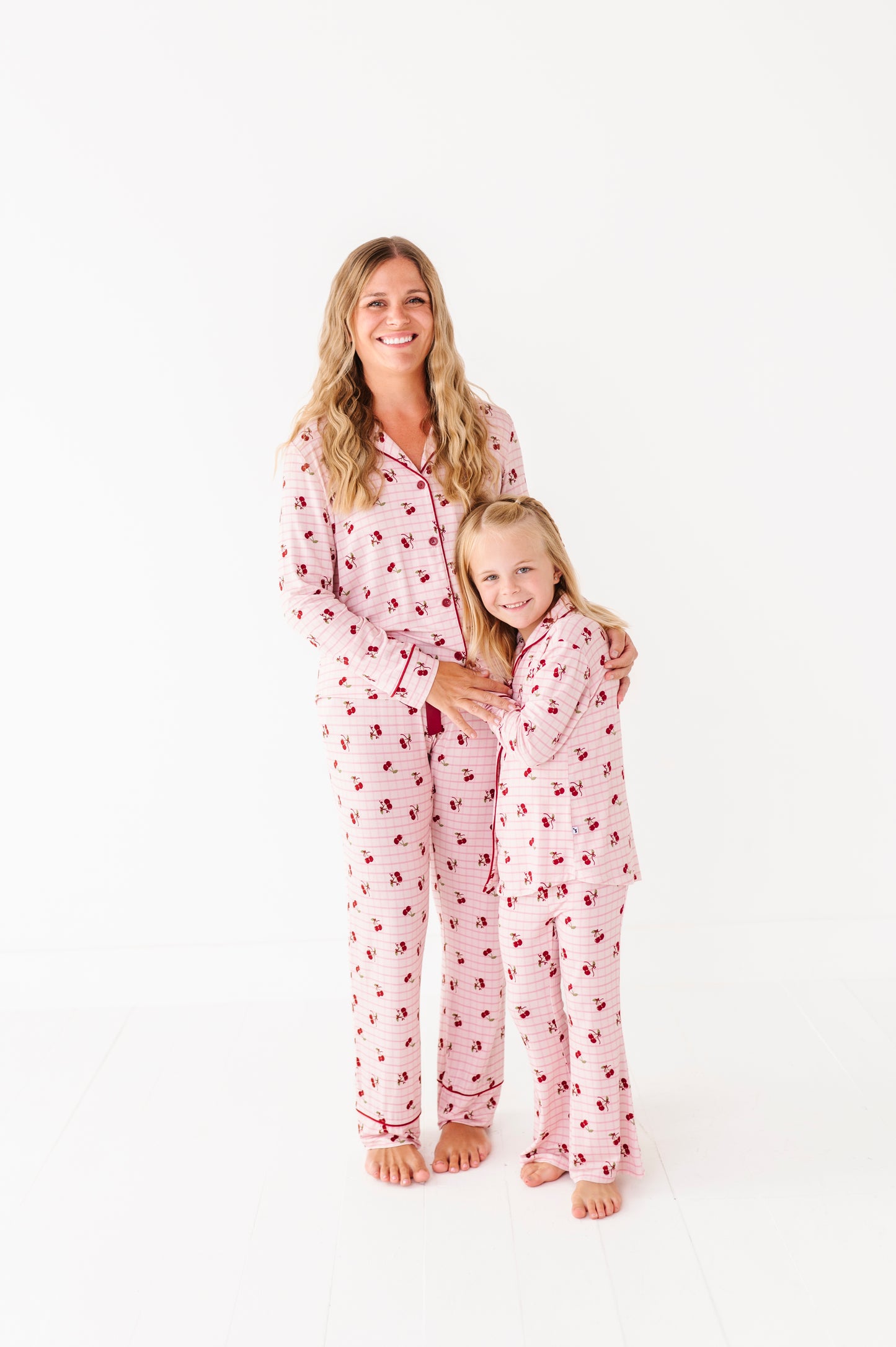 Woman and child wearing matching pink pajamas with red hearts on a white background