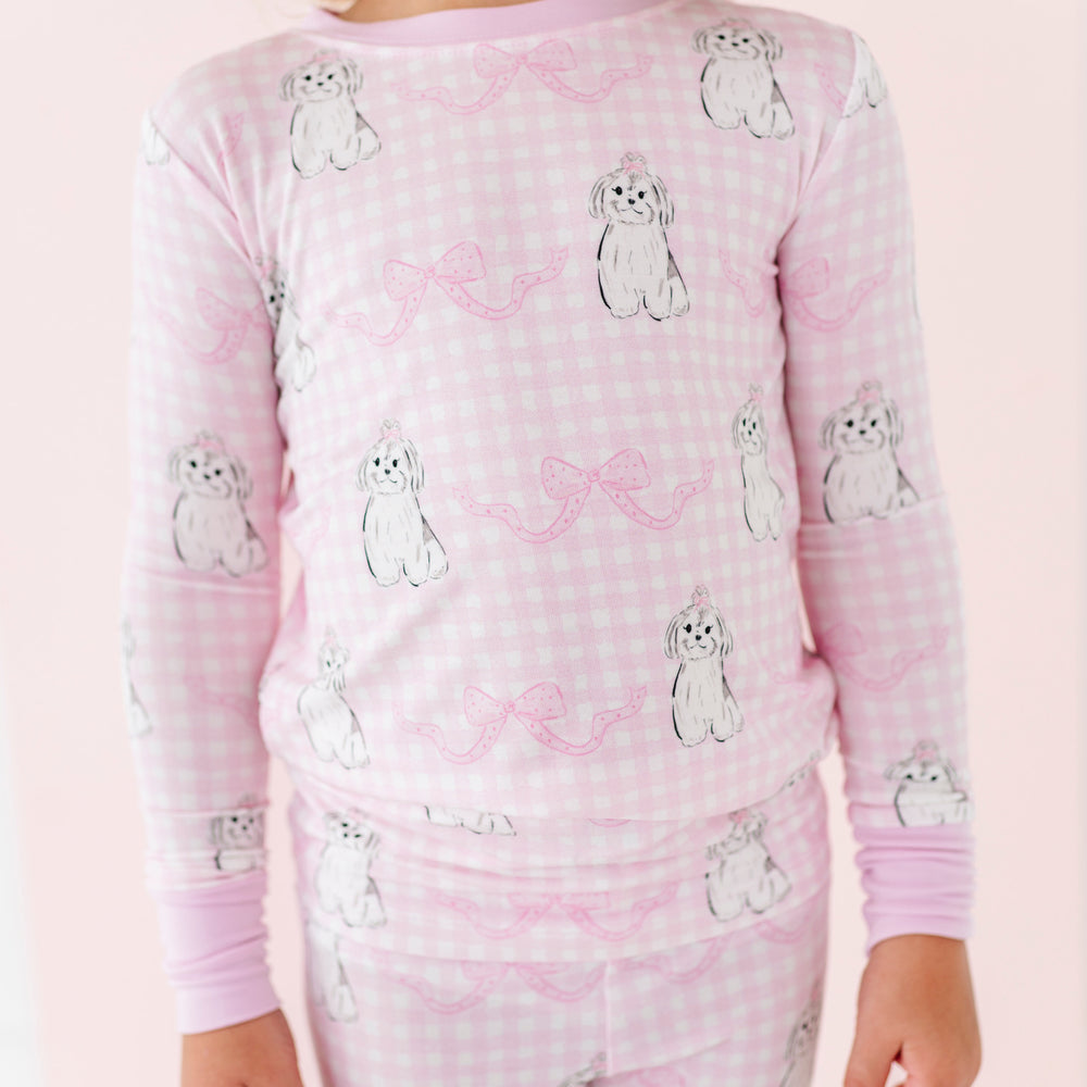 
                      
                        Child wearing pink pajamas withdog pattern on a light pink background
                      
                    