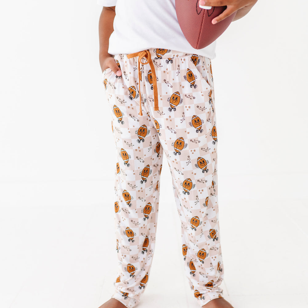 
                      
                        Person wearing patterned pajama pants holding a football on a white background
                      
                    